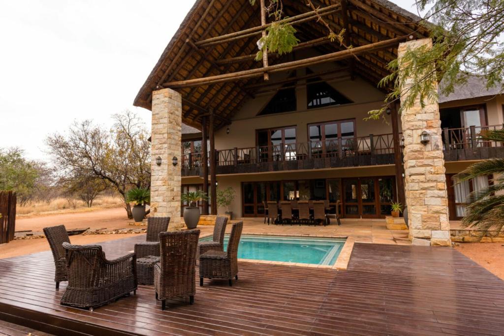 a house with a deck with chairs and a swimming pool at The Citrine House 33 in Mabula