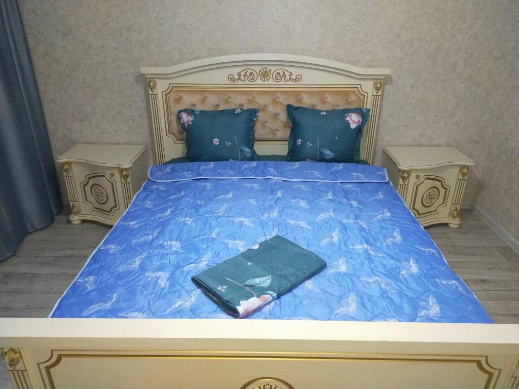 ein Bett mit blauer Decke und einem Buch darauf in der Unterkunft Отличная 3х комнатная квартира in Oral
