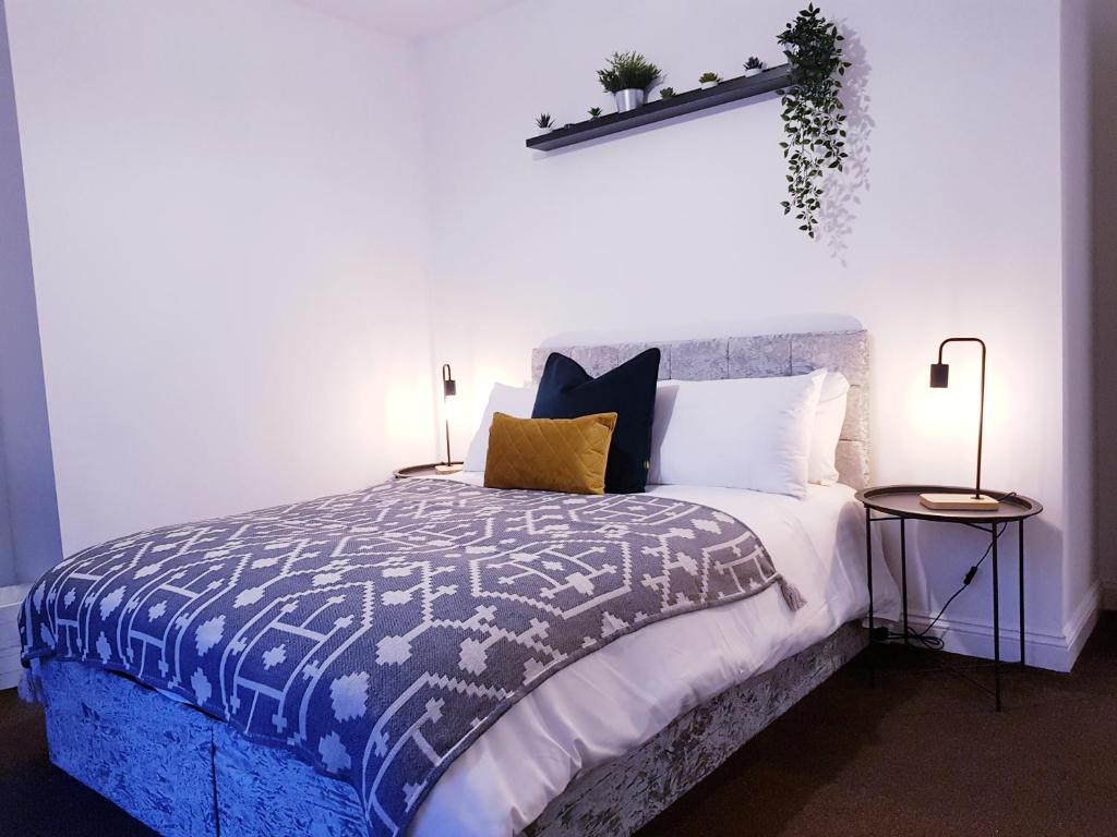 a bedroom with a bed with a blue and white comforter at The Birchington - 3 Bedroom Apartment & Workspace in Westoe