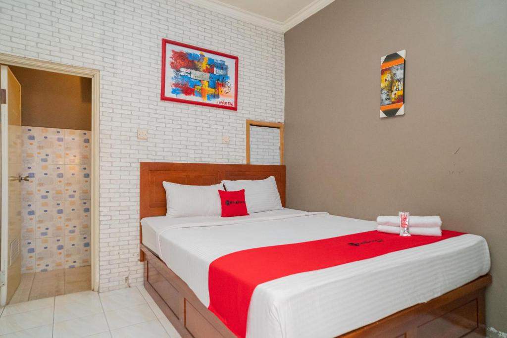 a bedroom with a large white bed with a red blanket at RedDoorz at Oro Oro Ombo Batu in Tlekung