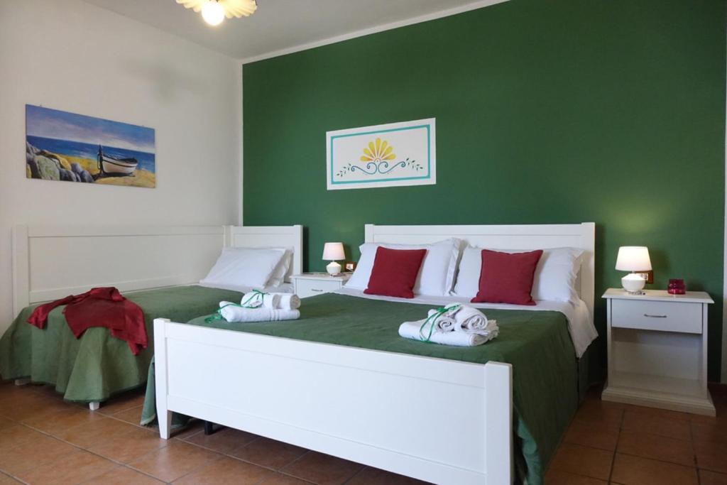 una camera con due letti e una parete verde di LEUCA TWENTY ROOMS a Leuca