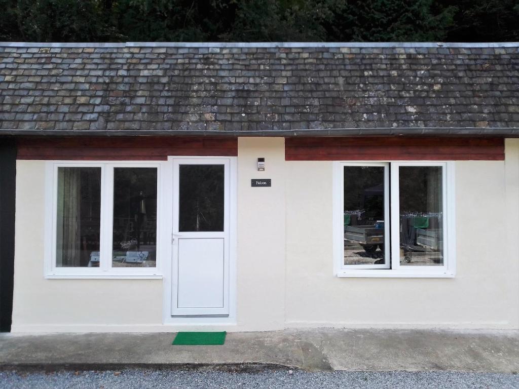 a small white house with a white door and windows at The House in the Woods in Plélauff