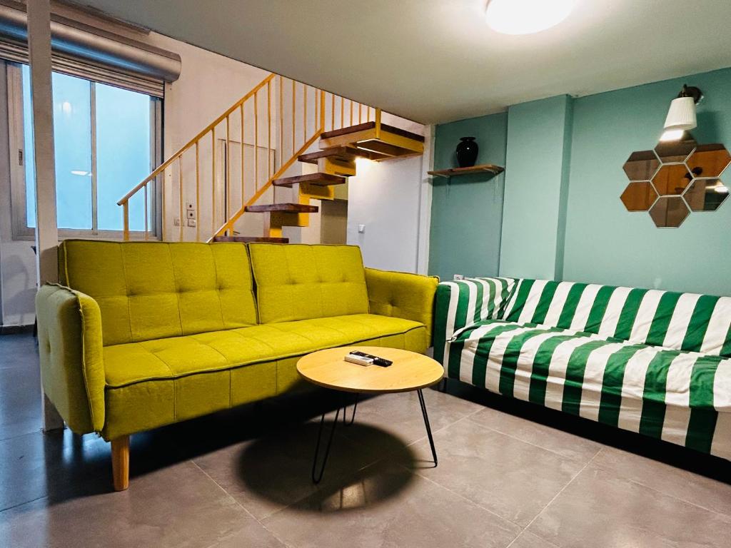 sala de estar con sofá amarillo y mesa en Lev Florentin Apartments, en Tel Aviv
