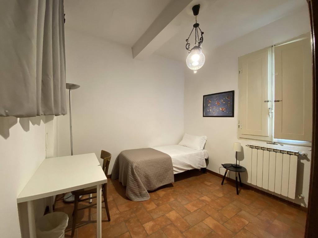 a small white room with a bed and a table at Accademia Apartment in Florence