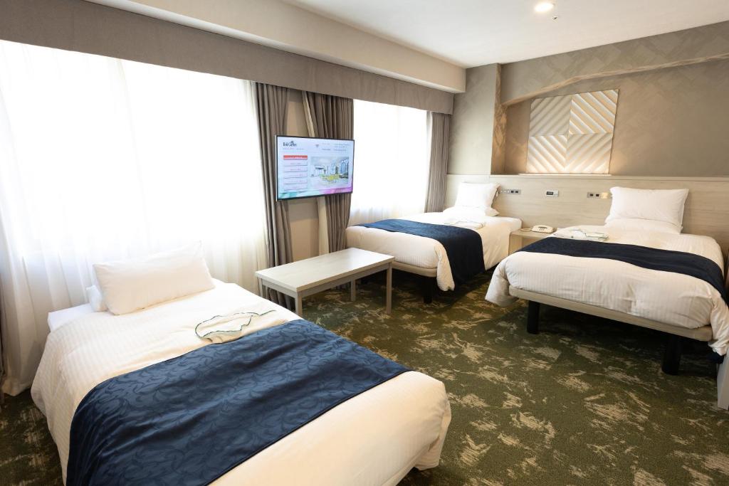 a hotel room with three beds and a flat screen tv at Hotel Rose Garden Shinjuku in Tokyo