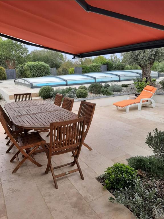 une table et des chaises en bois sous un parapluie rouge dans l'établissement ESMAEL, à Larmor-Baden