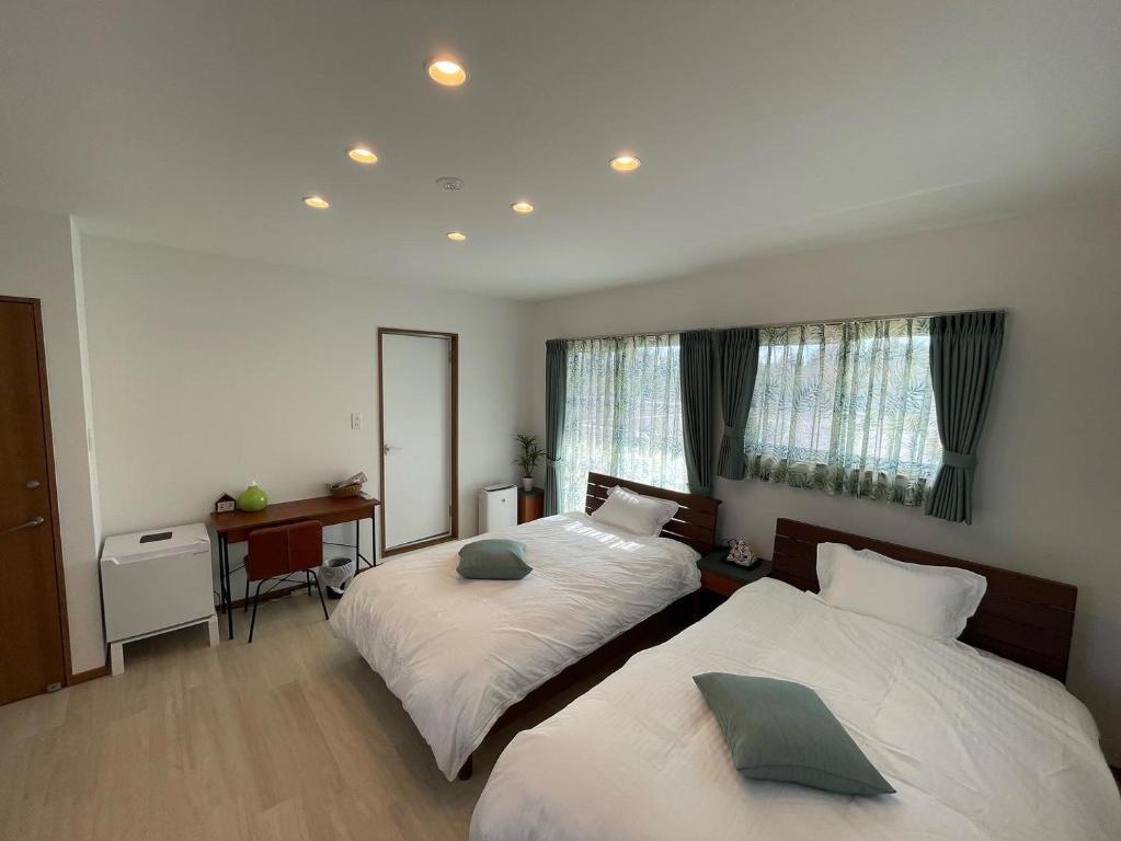 a bedroom with two beds and a desk and a mirror at Dining & Stay 38 Miyahira in Zamami