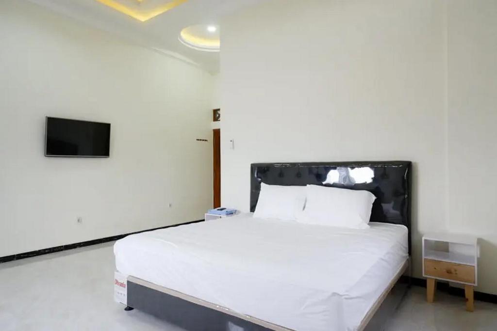 una camera da letto con un letto bianco e una tv di Griya Mataram Kotagede Mitra RedDoorz a Yogyakarta
