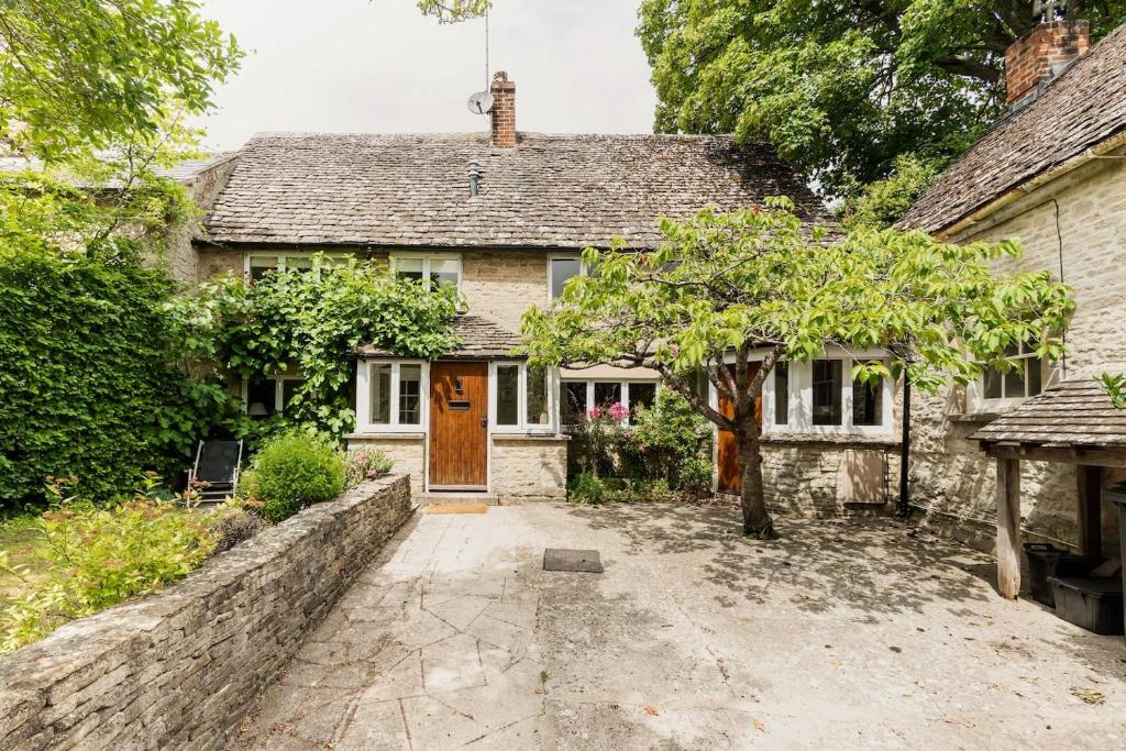 an old stone house with a wooden door at Architect Designed Cosy Cotswold Stone Cottage in Quenington