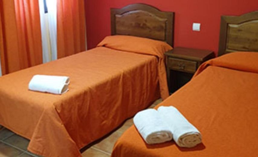 two beds in a hotel room with towels on them at Hostal El Hidalgo in Villaluenga