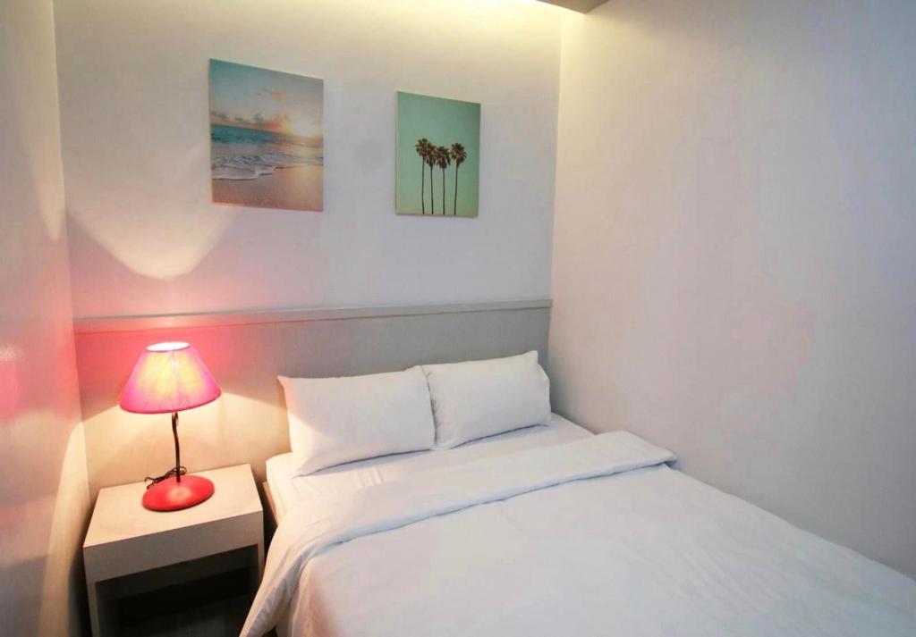 a small bedroom with a bed and a red lamp at SANDS Hotel Nasugbu in Nasugbu