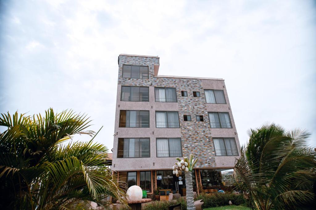 a tall building with palm trees in front of it at PLUS 33 HOTEL in Nungua