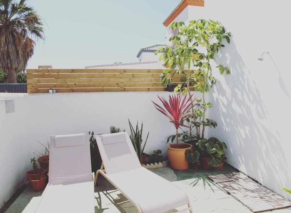 un patio con 2 sillas blancas y macetas en Casa frida, en Los Caños de Meca