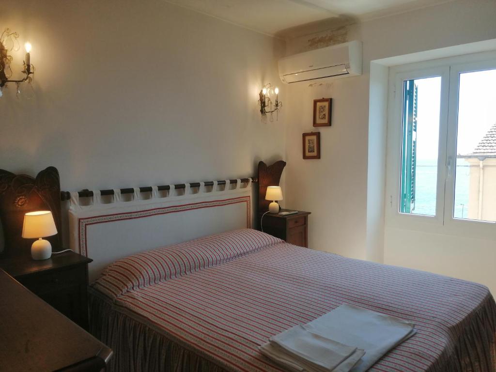 a bedroom with a bed with a striped bedspread and a window at Casa del Sole affacciato sul mare in Cervo