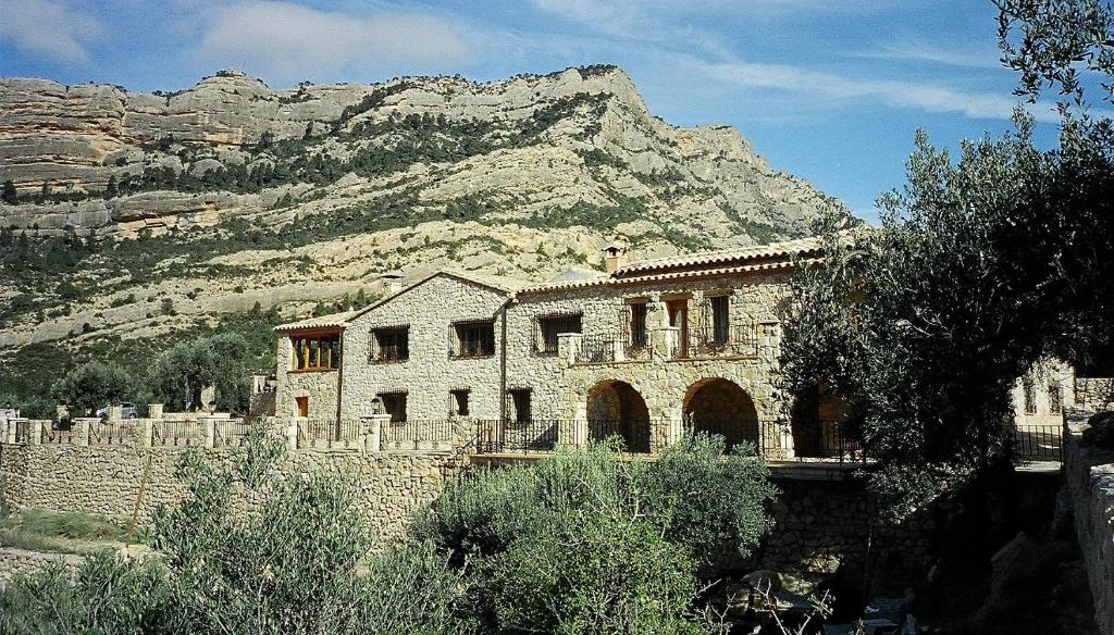 a stone building with a mountain in the background at Mas de la Vall del Frare in Gandesa
