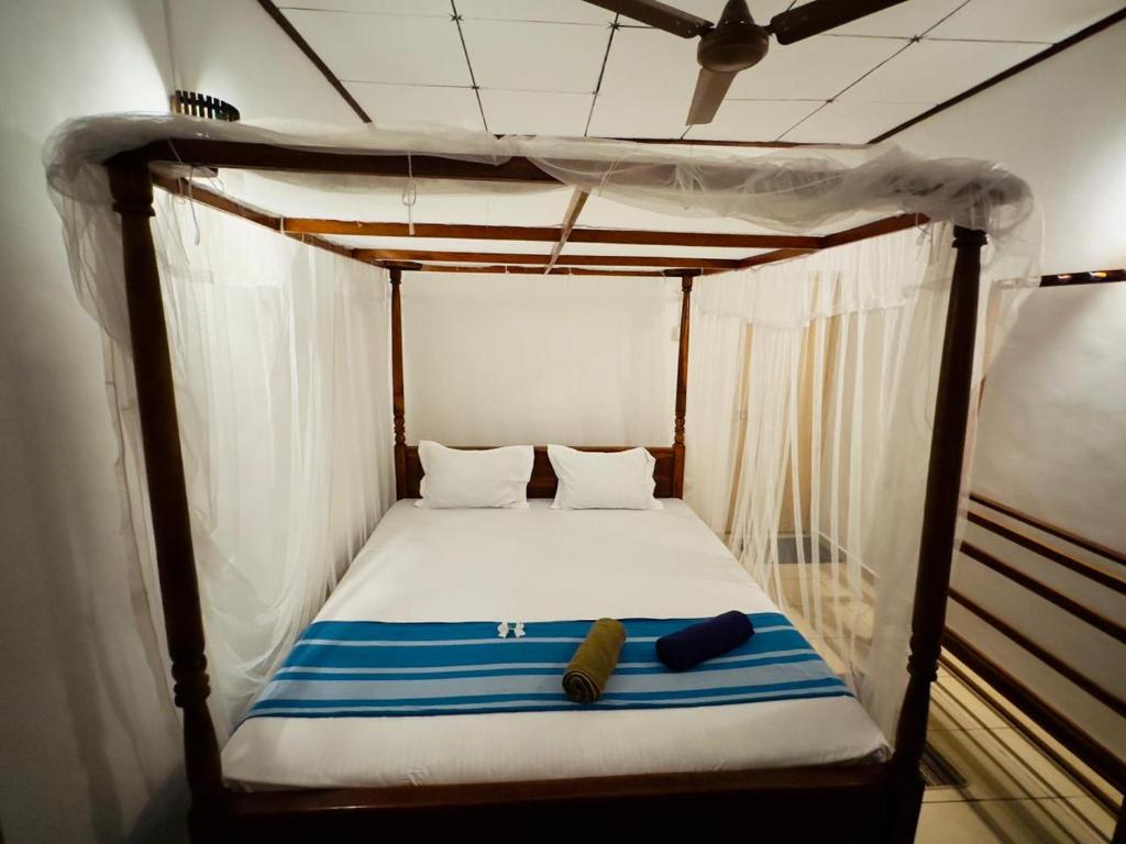 a canopy bed with two pillows and towels on it at Twice Happy Beach Garden in Tangalle