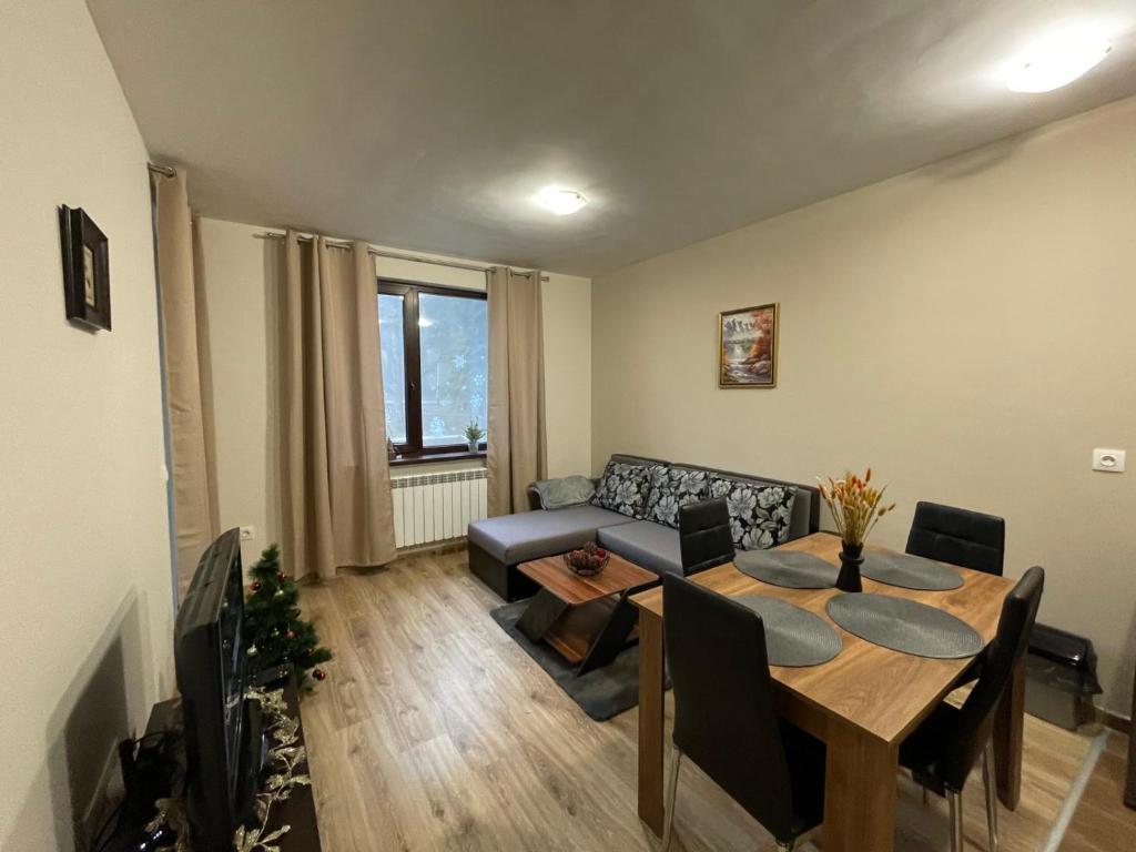 uma sala de estar com uma mesa e um sofá em Apartment E23 Borovets Gardens em Borovets