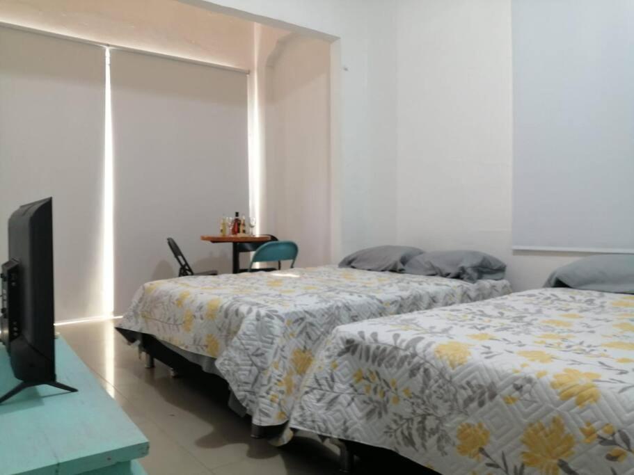 1 Schlafzimmer mit 2 Betten, einem Tisch und einem TV in der Unterkunft APARTAESTUDIO EN MANGA CARTAGENA in Cartagena de Indias