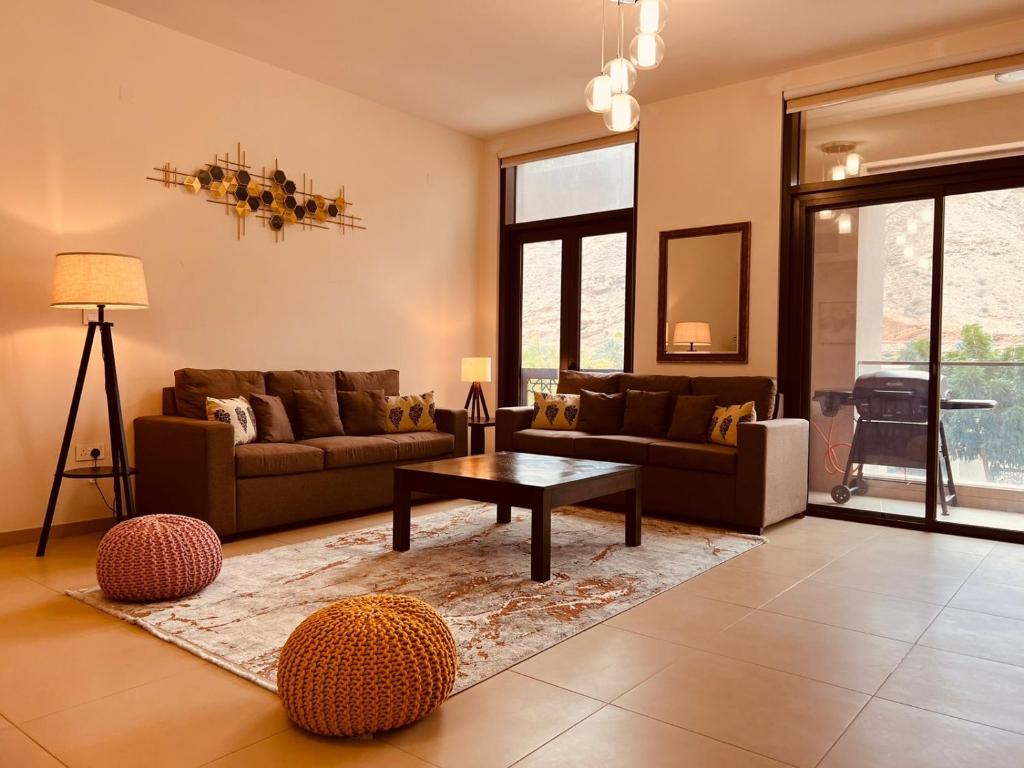 ONE 2BHK Elegant Apartment in Muscat Bay 03 في مسقط: غرفة معيشة مع أريكة وطاولة