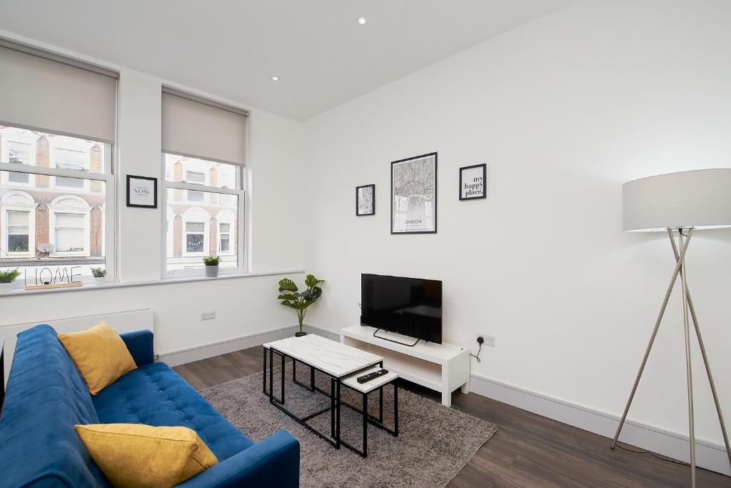 uma sala de estar com um sofá azul e uma televisão em High spec 2 Bed apartment w/parking available em Londres