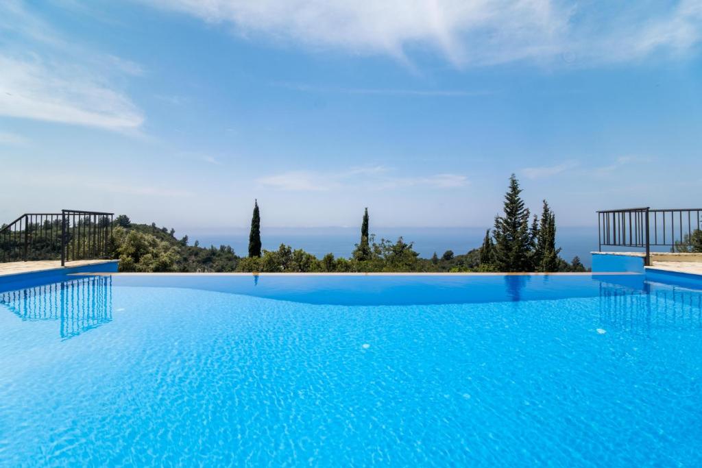 una gran piscina con agua azul y árboles en Sapphire Blue Villa, en Kalamitsi