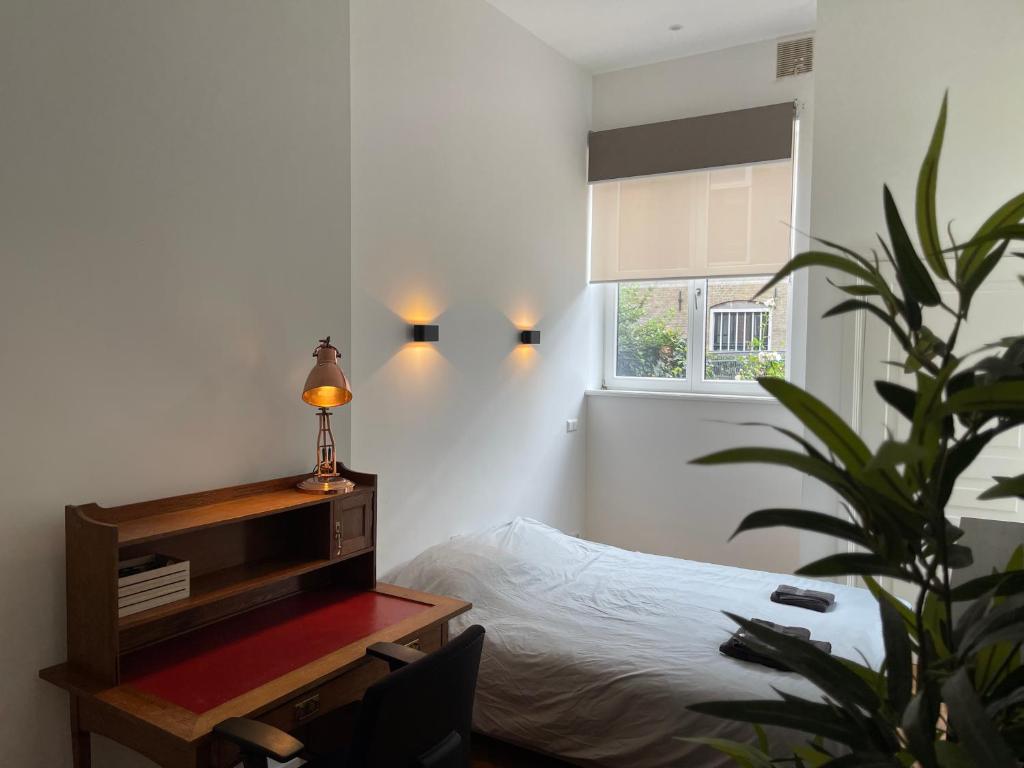 een slaapkamer met een bed en een bureau met een lamp bij Canal House in Historic City Center Gouda in Gouda