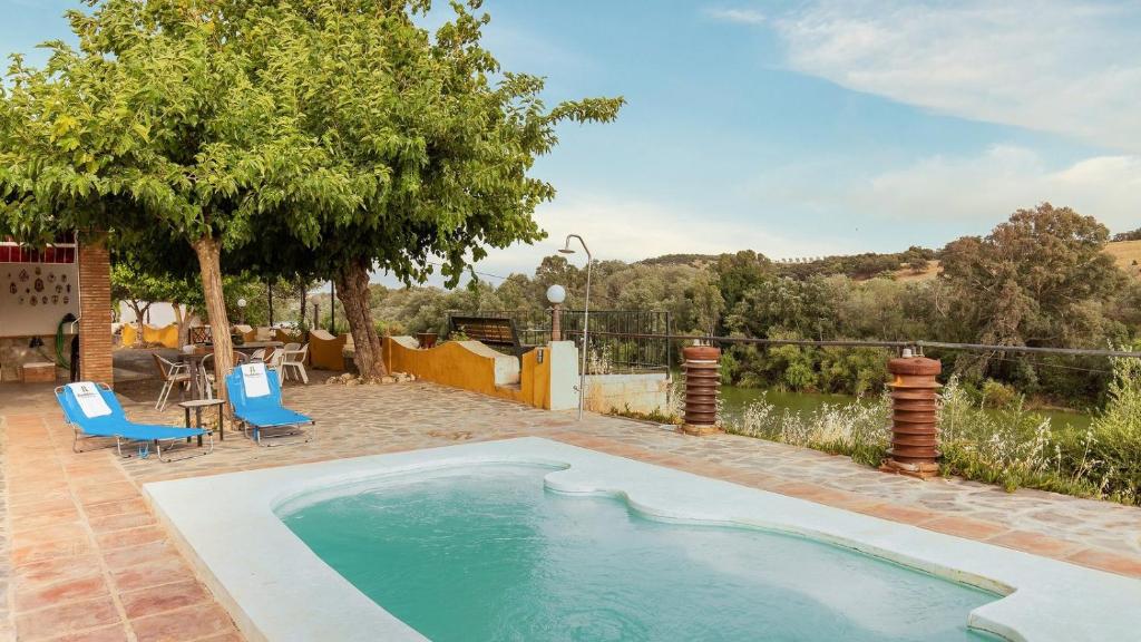 - une piscine avec deux chaises et un arbre dans l'établissement Alojamiento Rural El Salto Villafranca de Córdoba by Ruralidays, à Cordoue