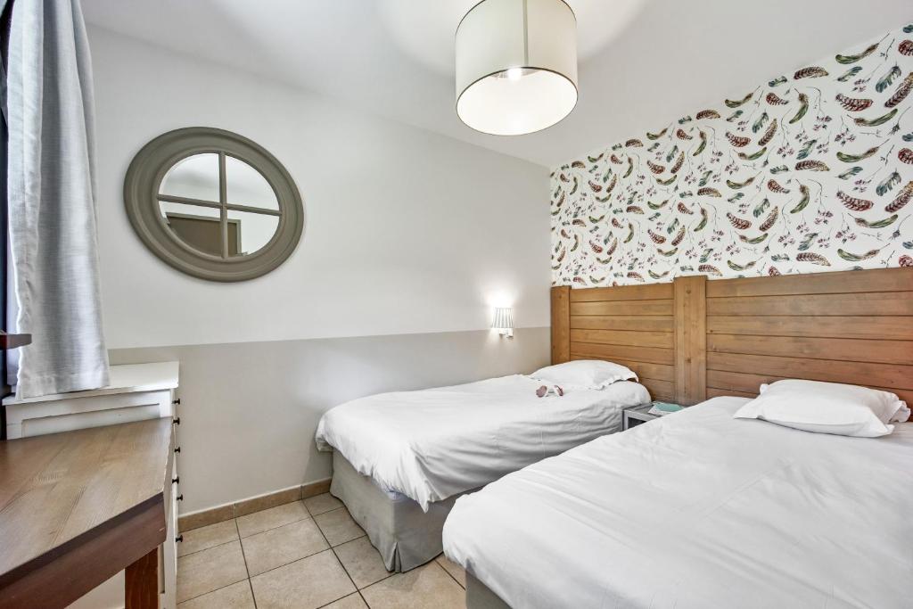 two beds in a room with a mirror at Pierre & Vacances Premium Residence & Spa Houlgate in Houlgate