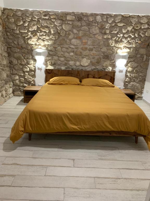 a bedroom with a bed and a stone wall at LA CASA DI PIETRA in Formia