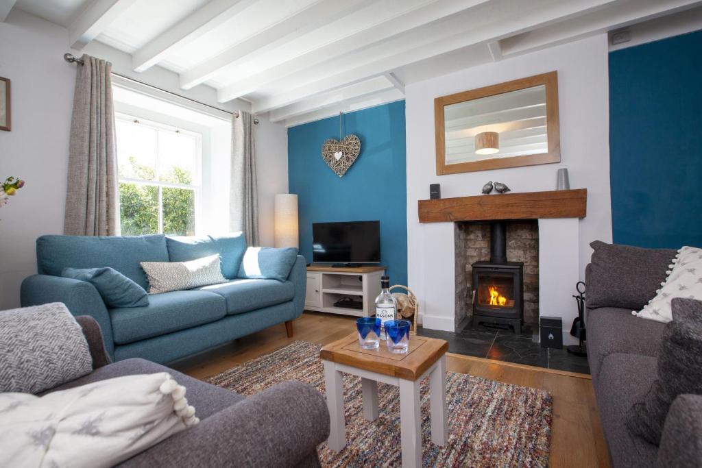 een woonkamer met blauwe muren en een open haard bij Moorside Cottage in Ampleforth
