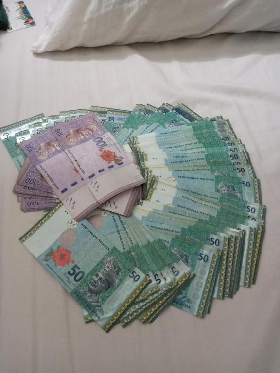 uma pilha de dinheiro sentado numa cama em รักหมดใจอพารทเมนต์ em Ban Khlong Nong Pru