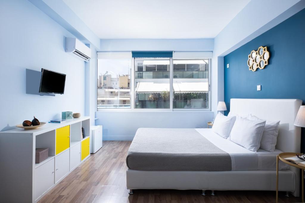 een blauwe en witte slaapkamer met een bed en een raam bij Enattica Syntagma Living in Athene
