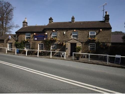 un gran edificio de ladrillo al lado de una carretera en The Plough Inn, en Hathersage