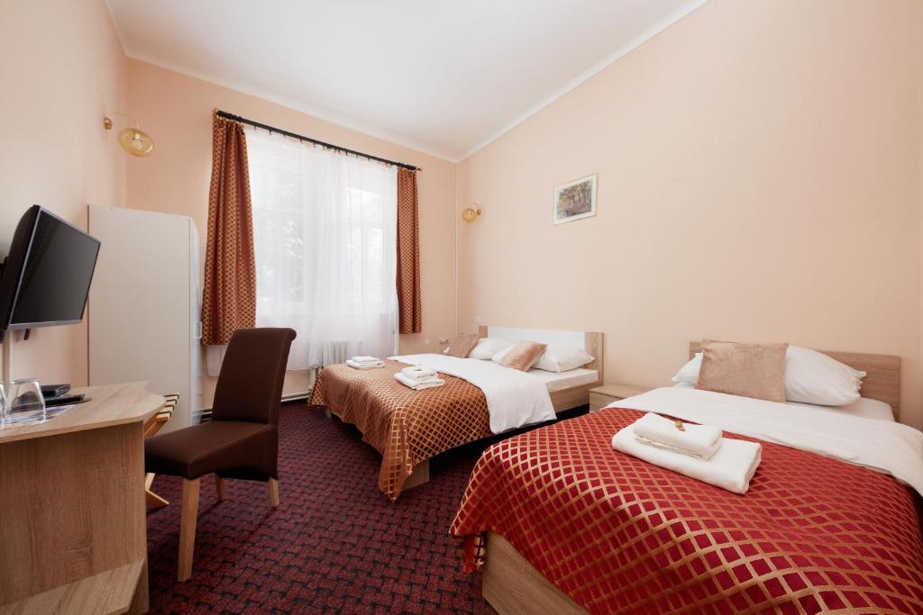 a hotel room with two beds and a desk at Hotel Roosevelt in Litoměřice