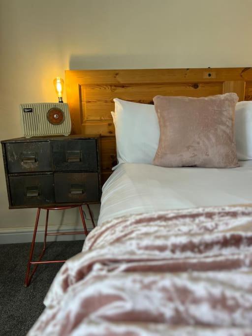 um quarto com uma cama e uma mesa de cabeceira com um relógio em The Cottage, Watergate, Sleaford em Lincolnshire