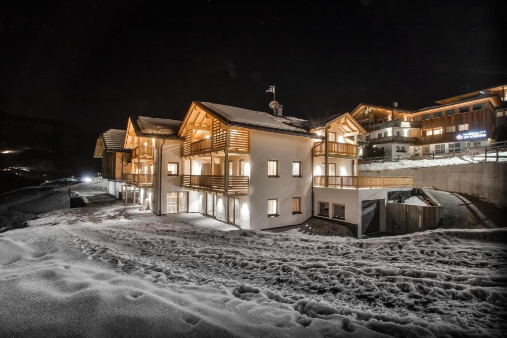 um grupo de casas na neve à noite em Bio Lüch Ruances em San Cassiano