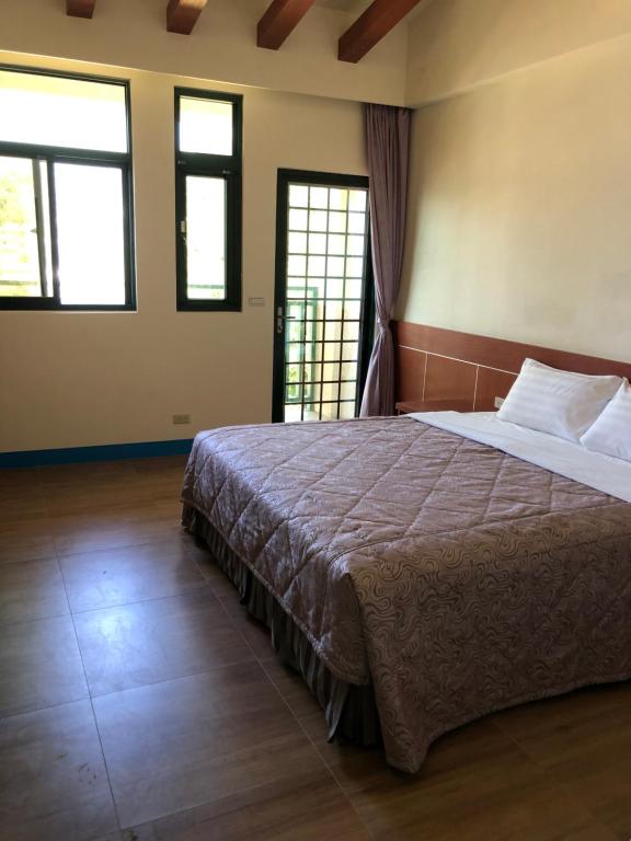 um quarto com uma cama grande e 2 janelas em Lohas Seaview B&B em Beigan
