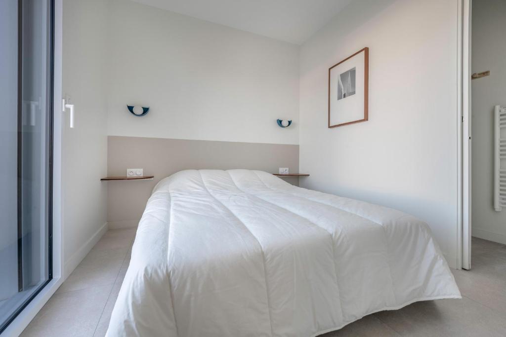 a white bedroom with a large bed with white sheets at Lumineuse et accueillante maison pour 8 personnes in Sarzeau