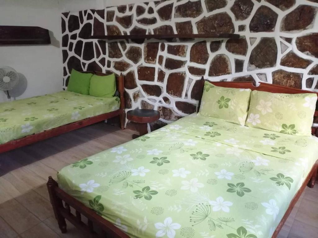 a bedroom with two beds and a stone wall at Casa Gundi y Tomas in Puerto Ángel