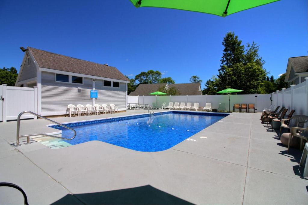 a pool with chairs and umbrellas next to a house at Killington Center Inn & Suites by Killington VR - 1 Bedrooms in Killington
