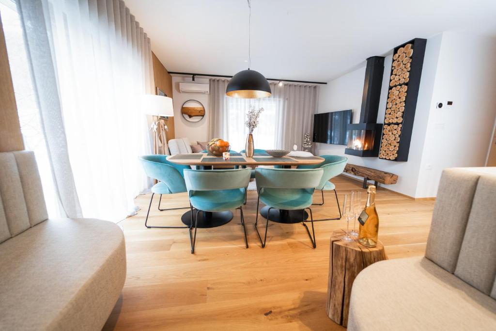 a dining room with a table and blue chairs at Bor in Bor Luxury Apartment with sauna & garden - Kranjska Gora in Kranjska Gora