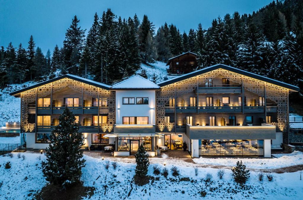 une grande maison dans la neige la nuit dans l'établissement Hotel Schmung, à Alpe di Siusi