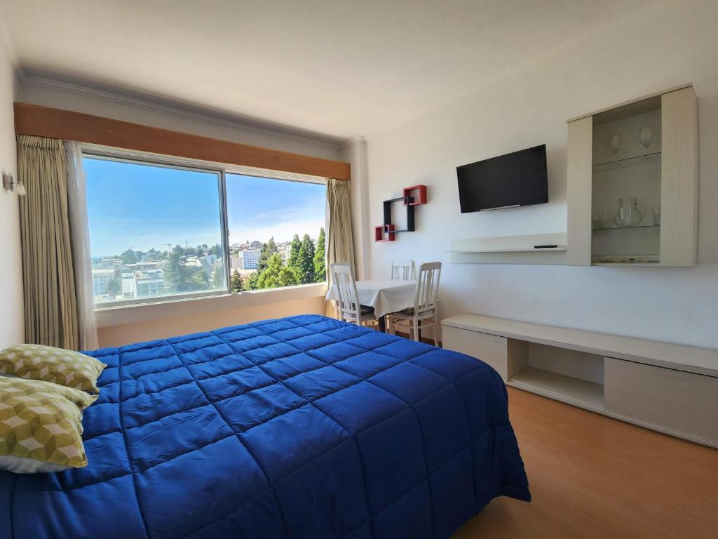 1 dormitorio con cama azul y ventana grande en Mirador del Lago Bariloche en San Carlos de Bariloche