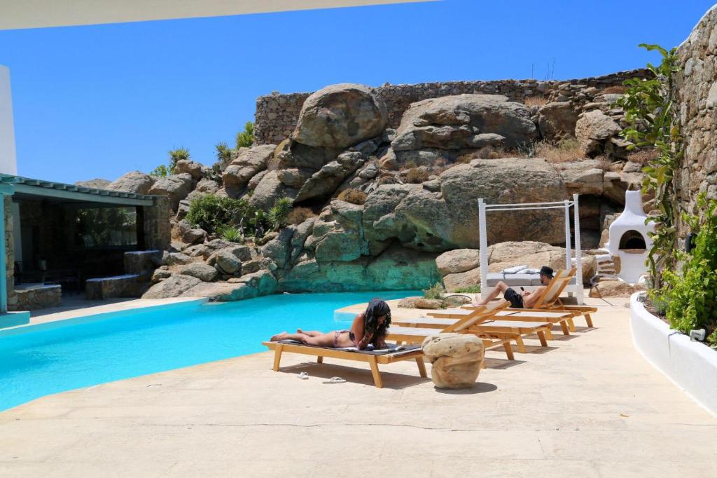 a group of people laying on lounge chairs next to a pool at Villa Delilah - Paradise Estate Mykonos - Views, Party, Memories 2026 in Paraga