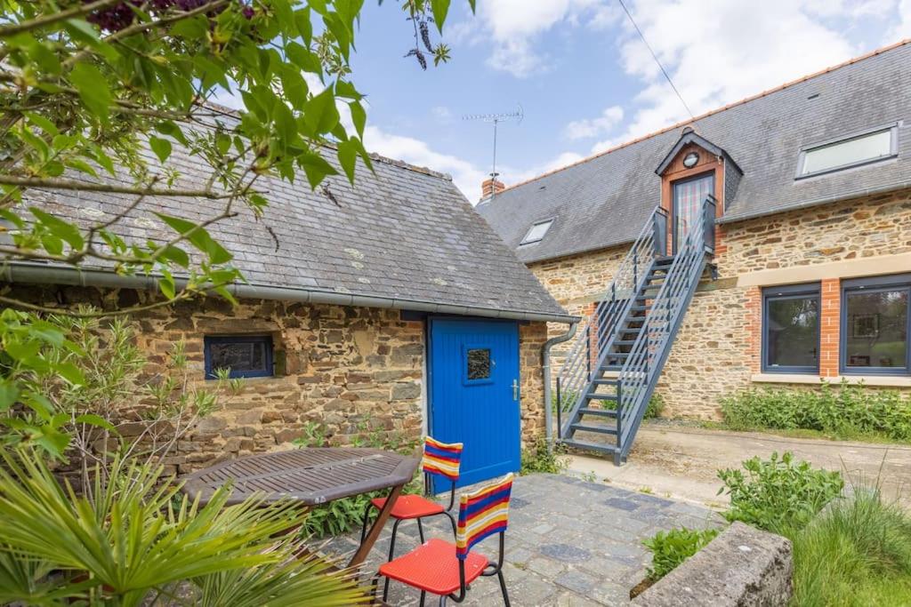 a brick cottage with a blue door and a table and chairs at Le Tertre de la Nouette in La Bosse-de-Bretagne