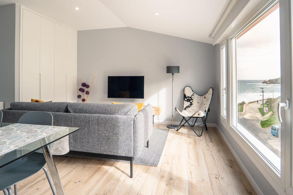 a living room with a couch and a large window at APARTAMENTO PEDRADOURO in Malpica