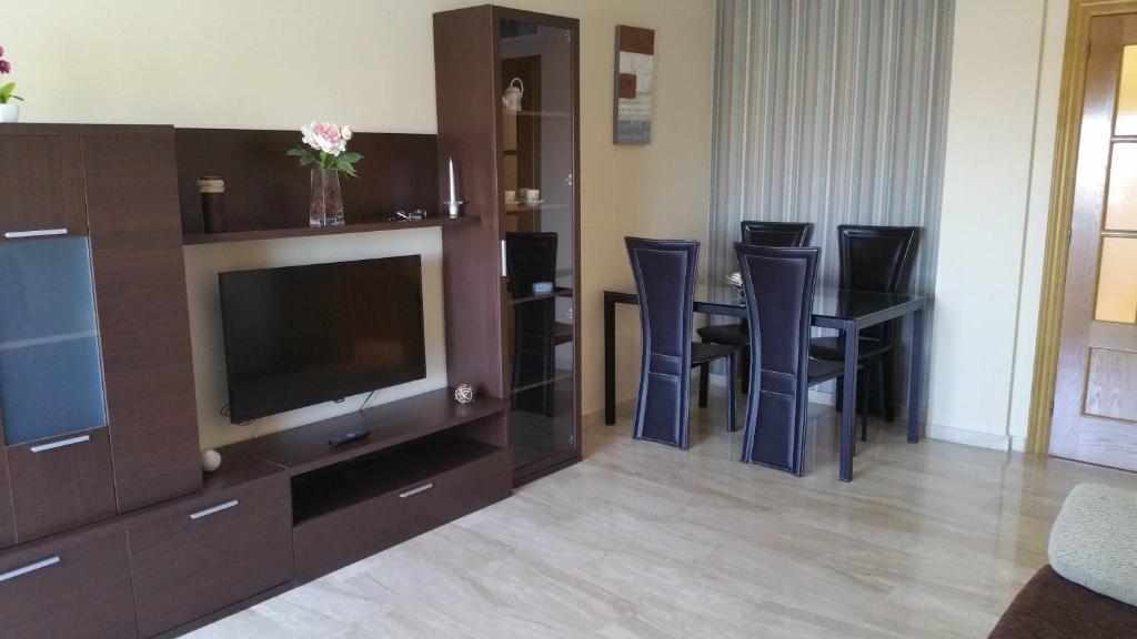 een woonkamer met een televisie en een tafel en stoelen bij GRANJA-CLIMATIZADO-Parking gratis in Jaén