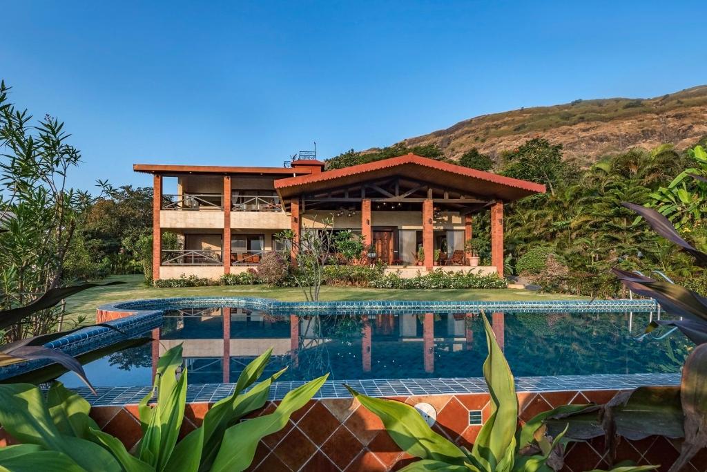 罗纳瓦拉SaffronStays Althea - 4 BRD Veg Only Villa In Pawna With Jacuzzi In Every Room的一栋前面有游泳池的房子