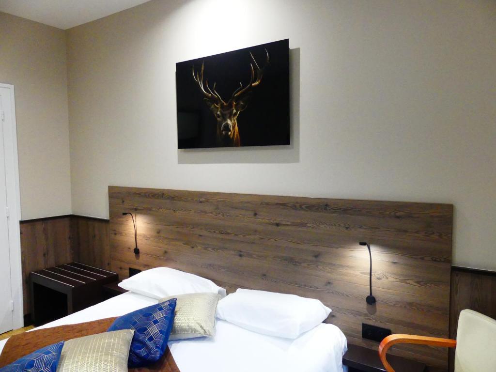 a bedroom with two beds and a deer head on the wall at Logis Hotel Des Bains in Gérardmer
