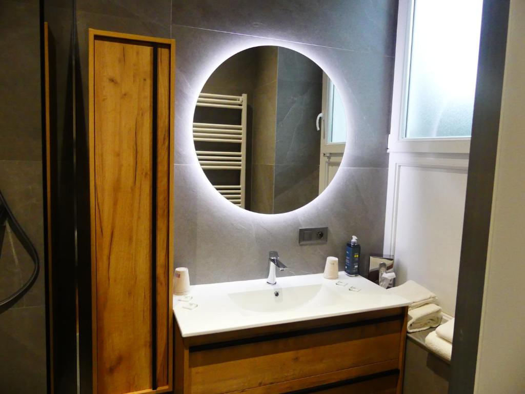 a bathroom with a sink and a mirror at Logis Hotel Des Bains in Gérardmer